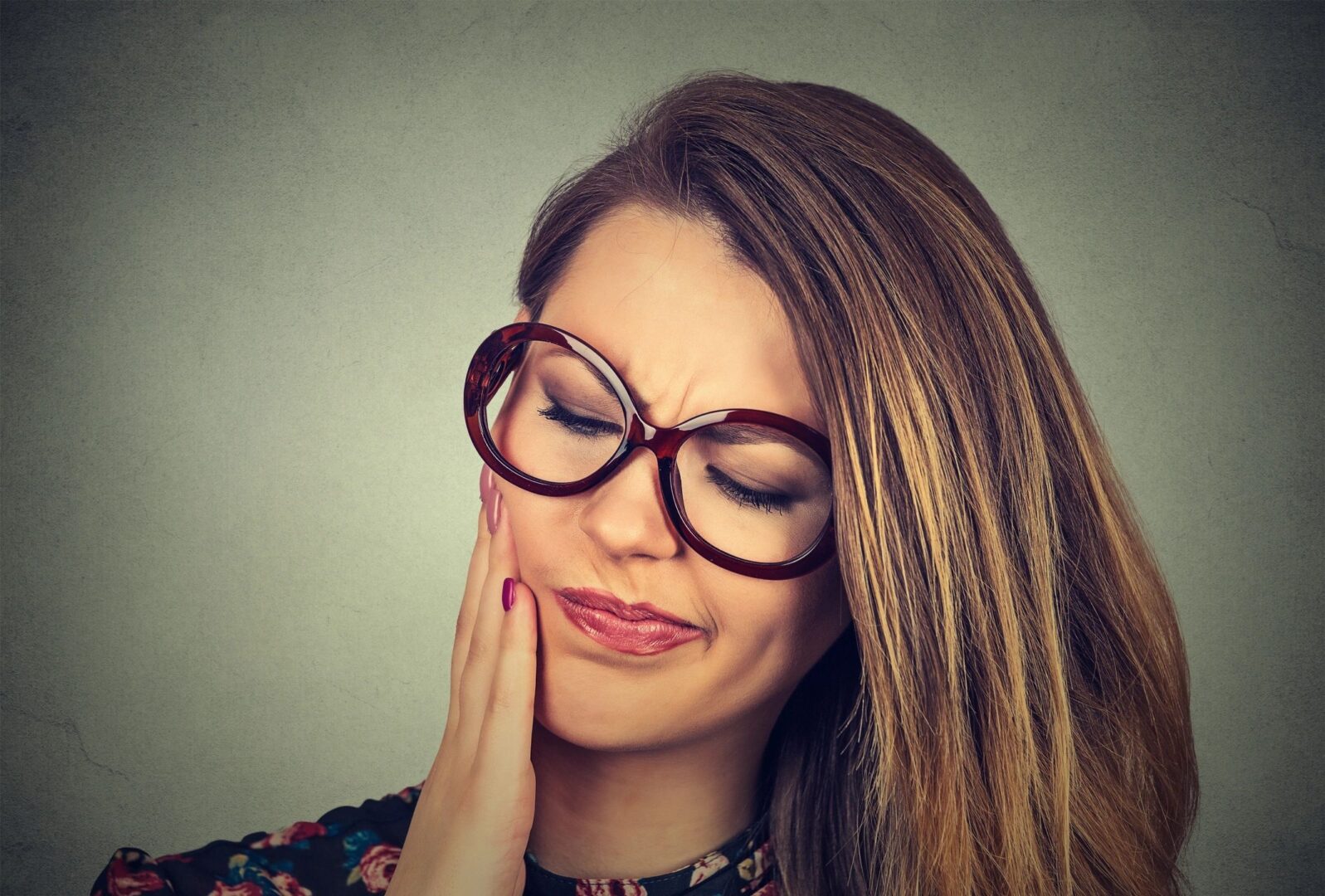 A woman with glasses is holding her face