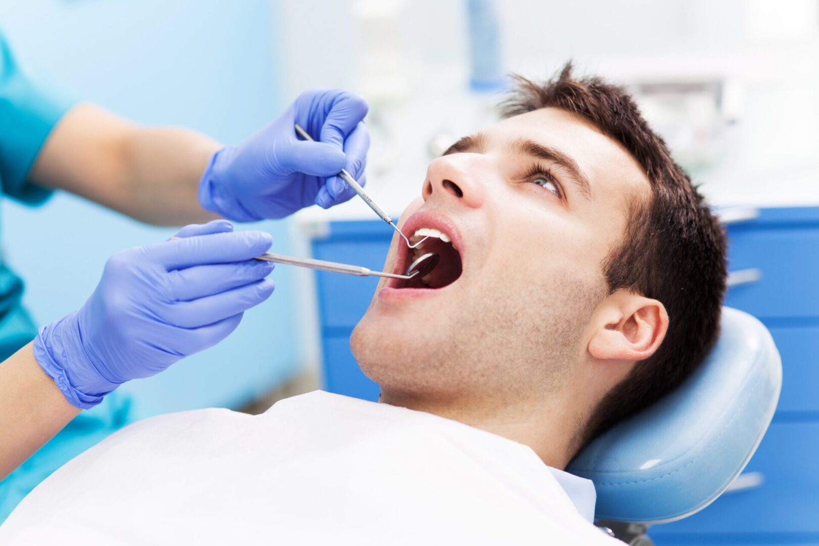 A man is getting his teeth examined by an dentist.
