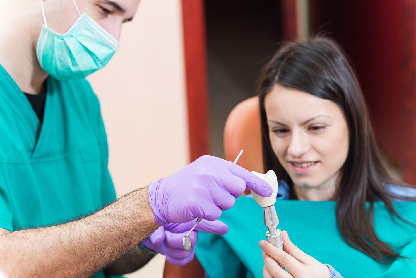 Dentist showing to his patient a dental implant with crown